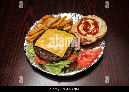 Delizioso cheeseburger con tutti i fissaggi su un panino Foto Stock