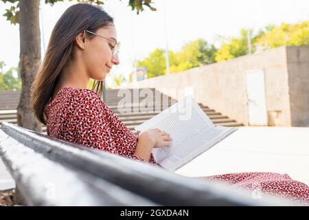 Giovane donna calma appoggiata sul fieno contro i monti sotto il cielo nuvoloso nelle Asturie Spagna Foto Stock