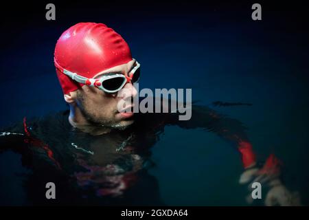 un vero nuotatore triatleta che ha una pausa durante l'allenamento al lago durante la notte buia Foto Stock