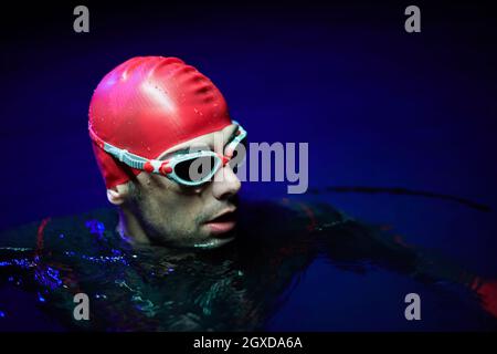 un vero nuotatore triatleta che ha una pausa durante l'allenamento al lago durante la notte buia Foto Stock