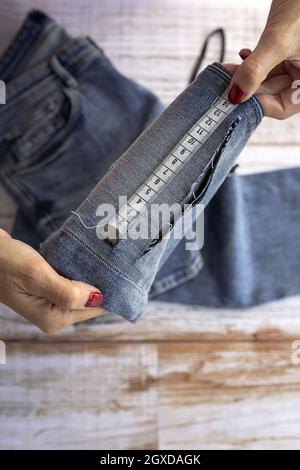 Da sopra di raccolto anonimo dressmaker femminile utilizzando nastro di misurazione mentre cucire jeans in atelier in giorno Foto Stock
