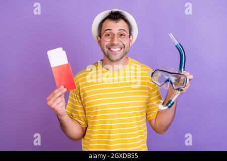 Foto di stupito shocked felice uomo positivo viaggio subacqueo occhiali passaporto isolato su sfondo viola colore Foto Stock