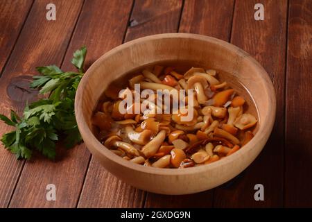 Funghi agarici al miele sottaceto fatti in casa con fette di cipolla in ciotola di legno. Funghi marinati in una ciotola su legno background.fermentato cibo sano Foto Stock