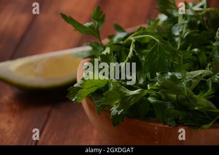 Il prezzemolo mazzo in una ciotola su sfondo di tavola di legno. Prezzemolo fresco su sfondo di legno. Crema di prezzemolo biologico su tavola rustica, cibo vegetariano overhea Foto Stock