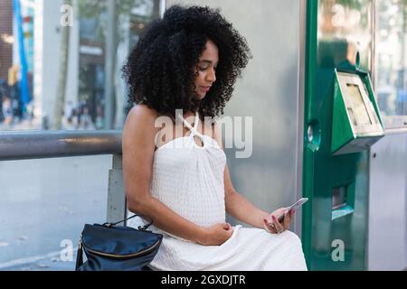 Crop anonimo artigiano femminile in grembiule nero sporco con spugna per riempire il disegno con pigmento su tavolozza ceramica su tavolo vicino a ciotole con vernice Foto Stock