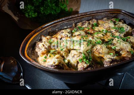 Polpette gratinate in un rustico arrostito con prezzemolo fresco sulla parte superiore e l'erba sullo sfondo Foto Stock