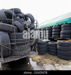 Molti pneumatici sono allineati su terreno bagnato. Sotto una tenda di tela verde Foto Stock