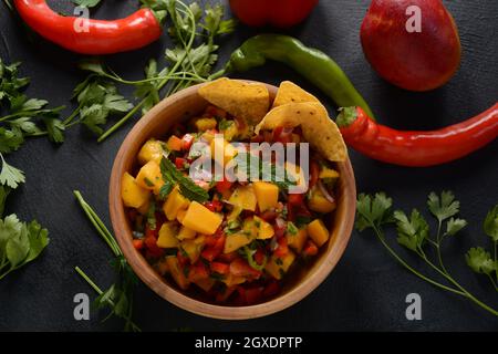 Salsa con mango, erbe, cipolle e peperoni, patatine di mais da vicino in una ciotola. Cibo messicano. Foto Stock