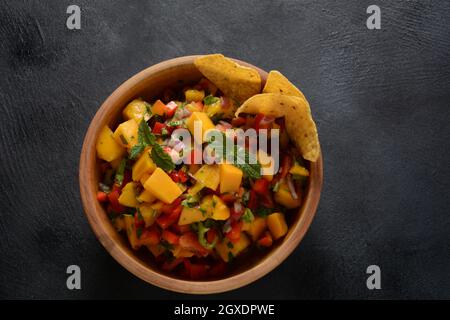 Salsa con mango, erbe, cipolle e peperoni, patatine di mais da vicino in una ciotola. Cibo messicano. Foto Stock