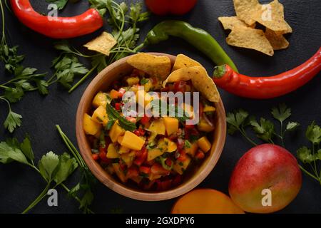 Salsa con mango, erbe, cipolle e peperoni, patatine di mais da vicino in una ciotola. Cibo messicano. Foto Stock