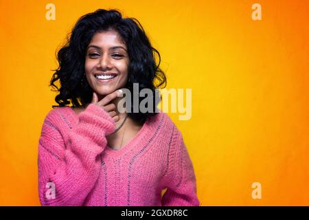 Bella Sri Lanka ragazza posa in piedi con giallo luminoso sfondo- La giovane donna sorride Foto Stock