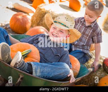 Due Ragazzini giocando in carriola alla Zucca Patch in un rustico di impostazione per il paese. Foto Stock