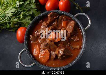 Manzo Bourguignon in una padella. Stufato con vino rosso, carote, cipolle, aglio, un bouquet garni, e guarnito con cipolle di perle, funghi e pancetta. Francese Foto Stock