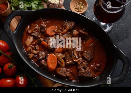 Manzo Bourguignon in una padella. Stufato con vino rosso, carote, cipolle, aglio, un bouquet garni, e guarnito con cipolle di perle, funghi e pancetta. Francese Foto Stock