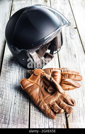 Accessori per motociclette di sicurezza. Guanti in pelle e casco su tavolo in legno. Foto Stock