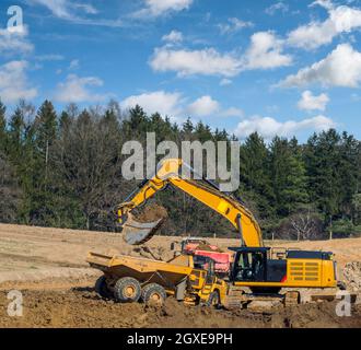 Falda terra gialla che riempie un autocarro in un cantiere Foto Stock