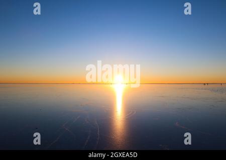 Frozen Oresund strait per quanto l'occhio può vedere, febbraio 2021 con le persone cifre in lontananza Foto Stock