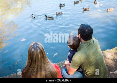 Razza mista Madre e Padre con Figlio al Parco Duck Pond. Foto Stock