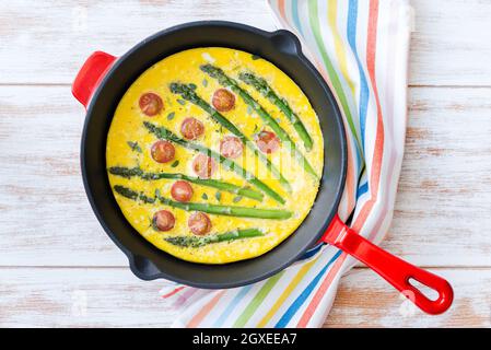 Vista dall'alto di freschi Frittata con asparagi verdi e pomodorini in padella Foto Stock