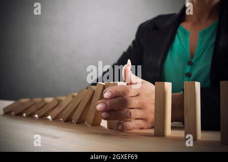 Imprenditrice si arresta una catena cadere come gioco di domino giocattolo. Concetto di prevenire le crisi e fallimento in business Foto Stock