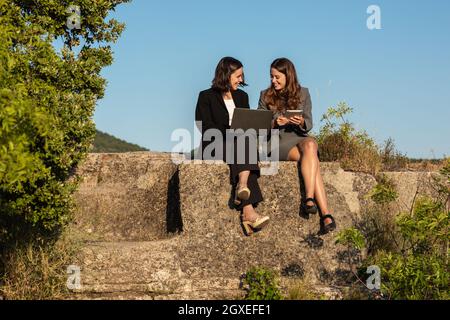 Donne d'affari che lavorano insieme a notebook e tablet in montagna Foto Stock