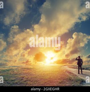 Imprenditore in un campo appare lontana per nuovo business durante il sunrise Foto Stock