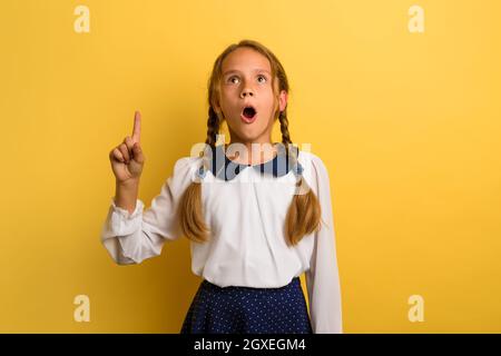 Il giovane studente ha un'espressione scioccata e indica qualcosa Foto Stock