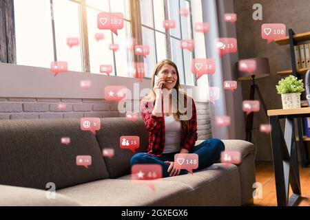 Una donna felice parla con tramite smartphone con messaggi, chat e icone degli utenti Foto Stock