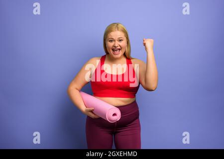 Fat ragazza fa palestra a casa. Soddisfatto e espressione con successo. Foto Stock