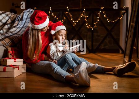 Cute figlia che scrive la lettera a Santa con sua madre Foto Stock