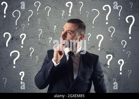 Confuso e pensieroso imprenditore preoccupati per il futuro, circondato da un punto interrogativo Foto Stock