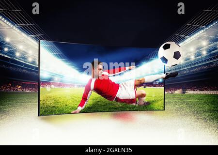 Il giocatore di calcio esce dalla tv per calciare il pallone Foto Stock