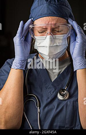 Femmina smorfie medico o infermiere indossando viso protettivo e indossare i guanti chirurgici. Foto Stock