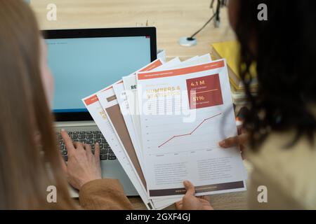 Documenti in mano di giovane economista femminile durante il lavoro di squadra con il collega Foto Stock