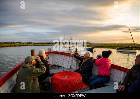 I passeggeri salgono a bordo di una barca charter Seal per ammirare e fotografare il paesaggio in condizioni di scarsa luce solare e tornare a Morston Quay, Norfolk, Inghilterra. Foto Stock