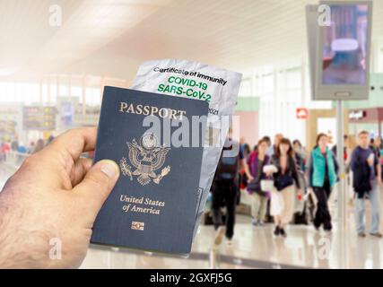 Mano che tiene un passaporto degli Stati Uniti con una carta stropicciata Coronavirus Covid 19 certificato di immunità offuscato aeroporto in background. Immunità da Covid-19. Foto Stock