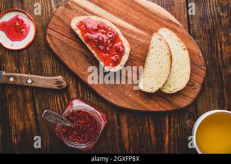 Brindate con marmellata di lamponi fatta in casa con una tazza di tè verde Foto Stock