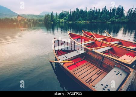 Barche rosse sul molo sul lago Strbske pleso. Vista mattutina del Parco Nazionale degli alti Tatra, Slovacchia, Europa. Foto Stock