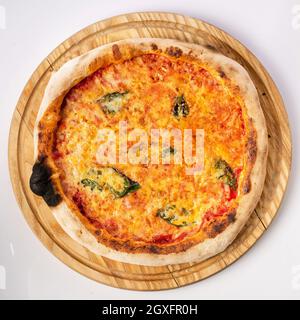 Vista dall'alto della pizza calda su un piedistallo in legno. Pizza Margarita . Base di pomodoro e molta mozzarella, il sapore del formaggio olandese e del basilico fresco. Foto Stock