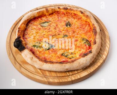 Vista dall'alto della pizza calda su un piedistallo in legno. Pizza Margarita . Base di pomodoro e molta mozzarella, il sapore del formaggio olandese e del basilico fresco. Foto Stock