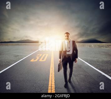 Uomo d'affari cammina su una strada sconosciuta per una nuova avventura al tramonto. Concetto di nuove opportunità e determinazione Foto Stock