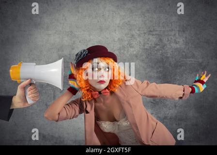 Il clown divertente sente un megafono con un messaggio importante Foto Stock