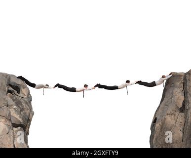 Uomini d'affari che lavorano insieme per formare un ponte tra due montagne Foto Stock