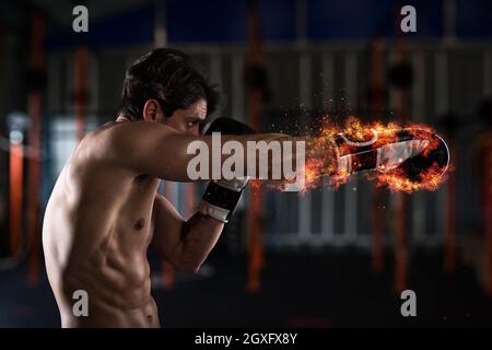 Determinato e fiducioso boxer con fiery guantoni da pugilato Foto Stock