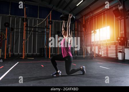 Determinata ragazza atletica lavora fuori al gym con un disco del barbell Foto Stock