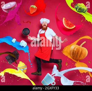 Lo chef è circondato da cibi e liquidi colorati. Foto Stock