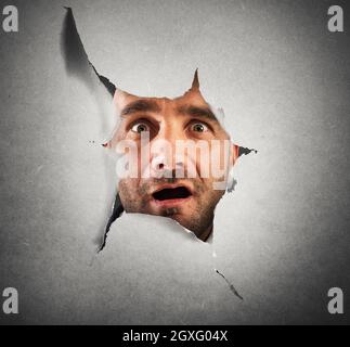 Uomo che sbucca attraverso un buco qualcosa di scioccante Foto Stock