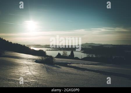 Lago, campi innevati e tramonto: scenario a Wallersee, Austria Foto Stock