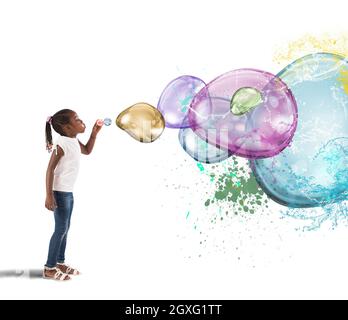 La ragazza piccola fa le bolle colorate grandi del sapone Foto Stock