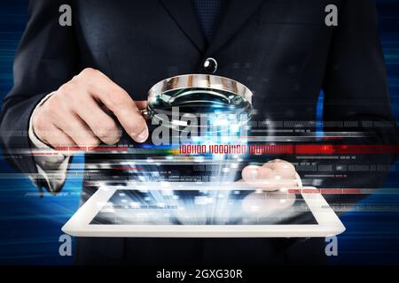 L'uomo guarda la lente d'ingrandimento lo schermo di un tablet Foto Stock